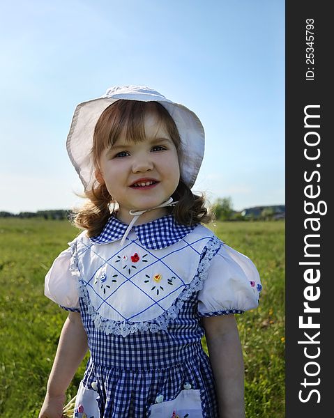 Happy little girl stands on green field