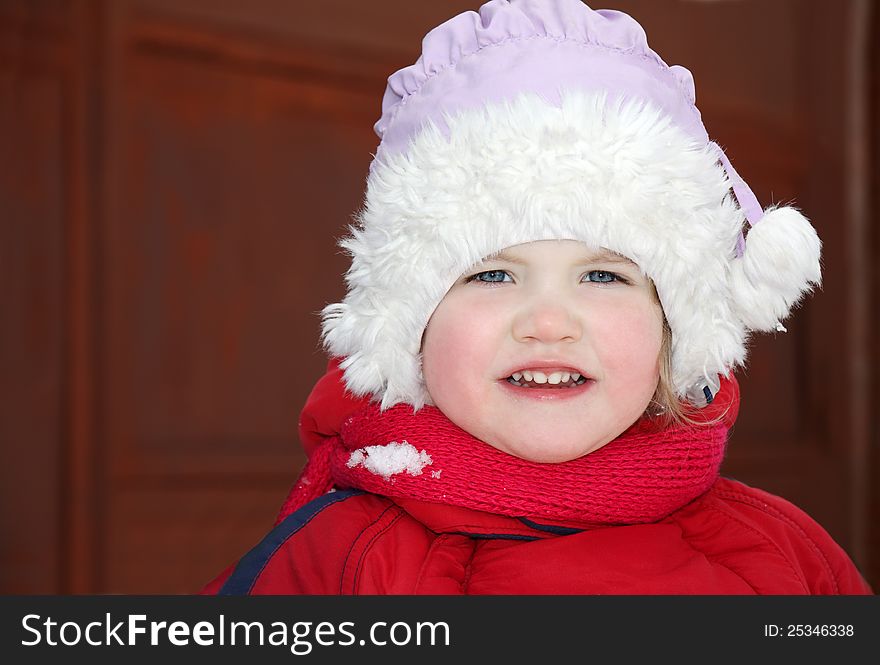 Cute little girl wearing warm clothing stands and looks at camera. Cute little girl wearing warm clothing stands and looks at camera