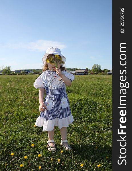 Little girl hides her face in yellow dandelions