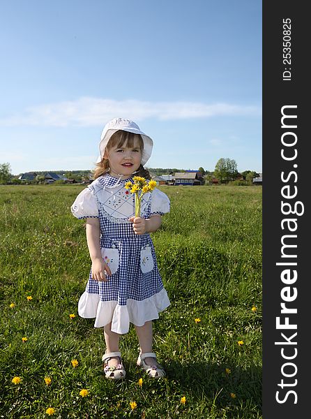 Happy little girl holds yellow dandelions