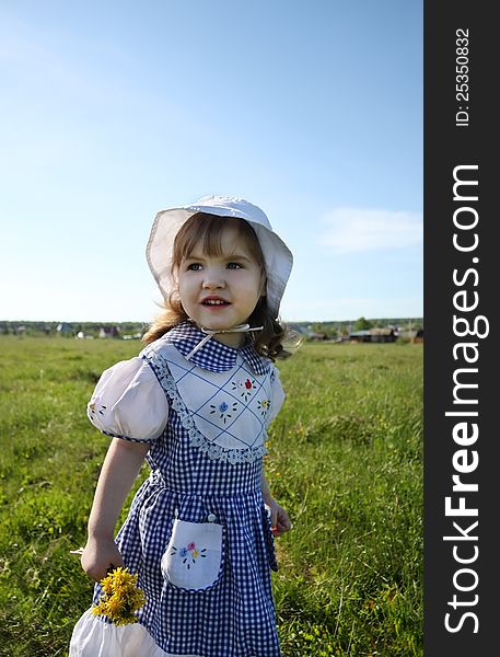 Little girl looks into distance on green field