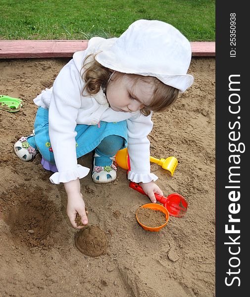 Little Cute Girl Plays In Sandbox