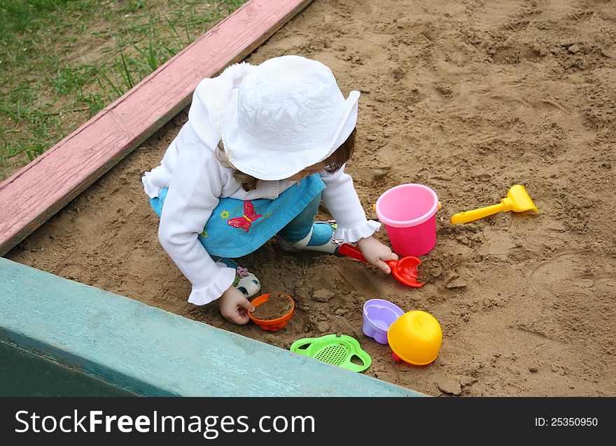 Llittle girl plays in sandbox at playground