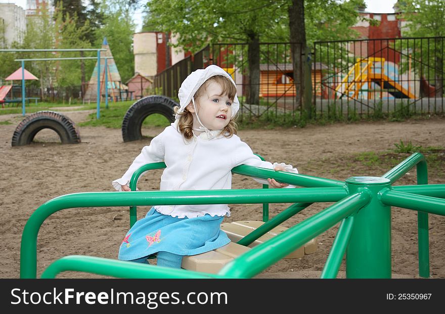 Pensive Little Girl Rides On Small Carousel