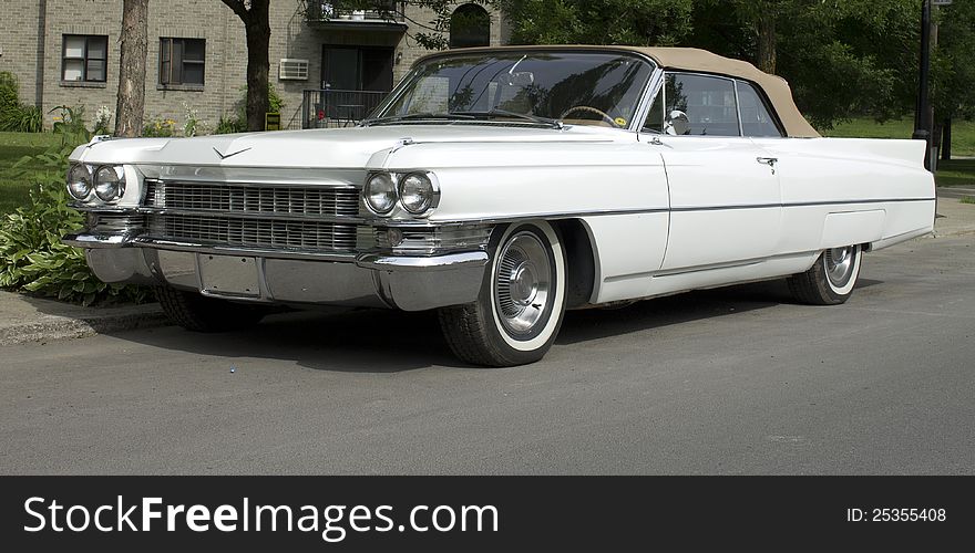 A white 60's classic convertible american car with white wall tires and beige leather top. A white 60's classic convertible american car with white wall tires and beige leather top