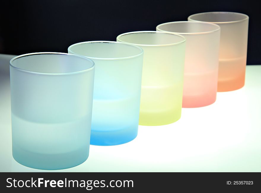 Colorful glasses on bar table . Rainbow transparent composition against black background. Colorful glasses on bar table . Rainbow transparent composition against black background