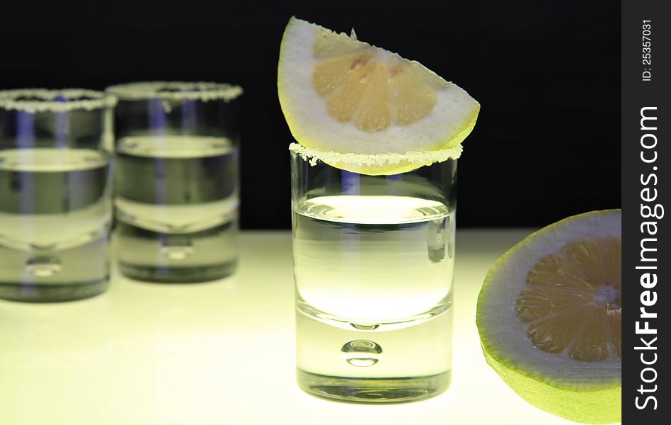 Tequila glasses ready on lighted bar table with salt and lemon