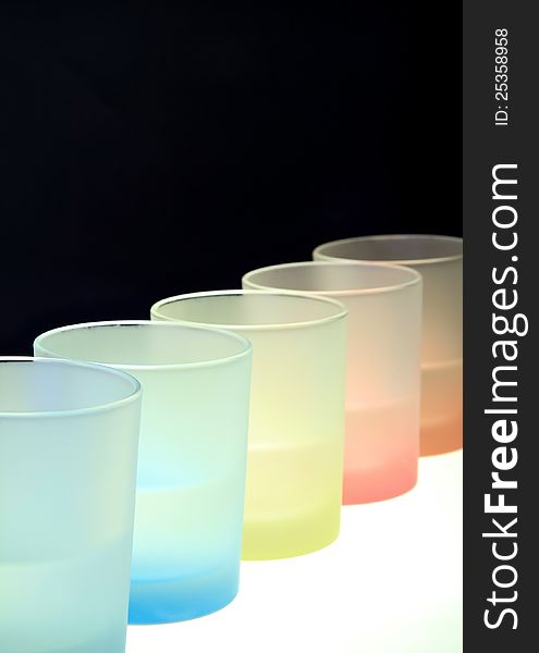 Colorful glasses on bar table . Vertical shot against black background. Colorful glasses on bar table . Vertical shot against black background