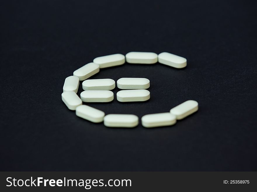 Euro sign written with pills on black background
