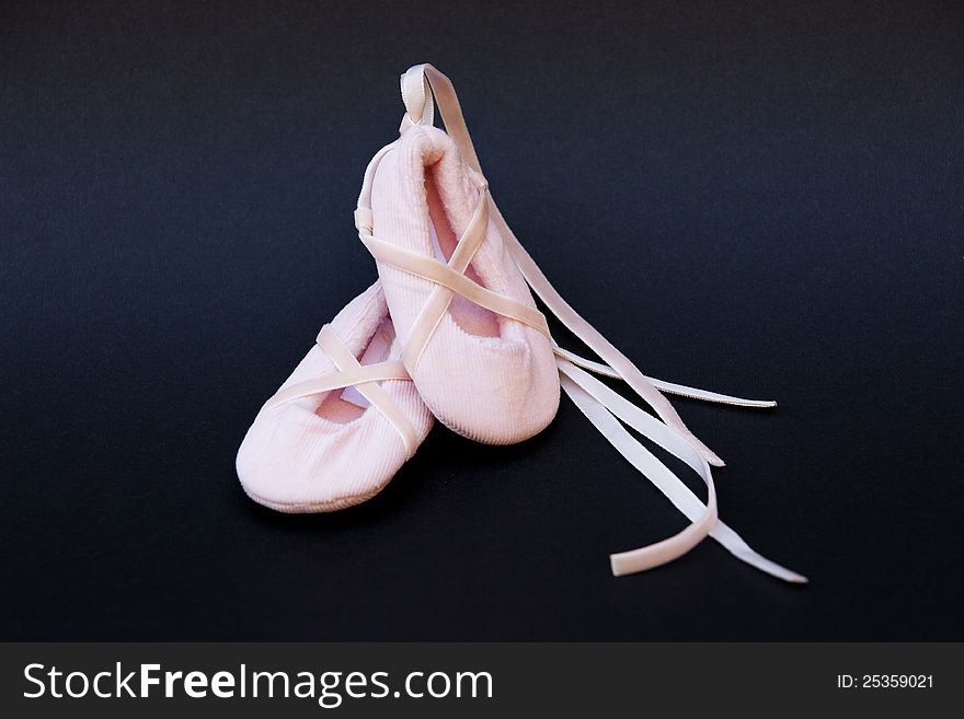 Newborn ballet shoes on black background