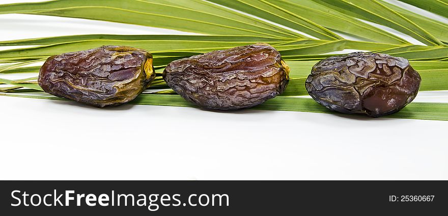 Ripe dates and green palm's leaves isolated on white background. Ripe dates and green palm's leaves isolated on white background