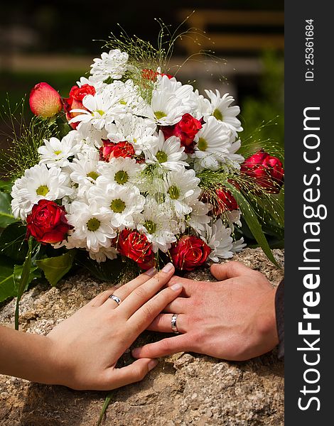 Wedding rings on their hands with flowers.