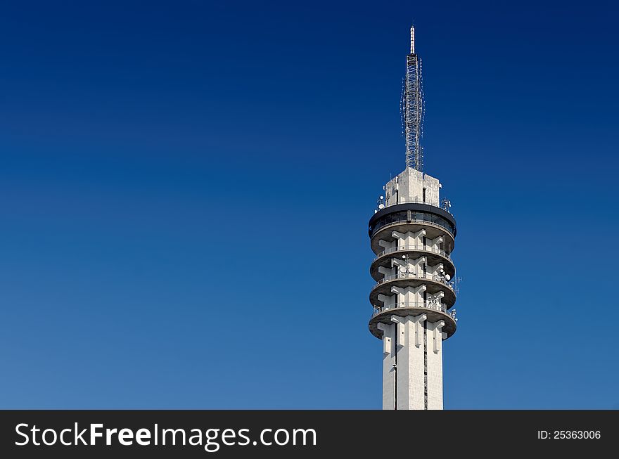 Large concrete telecommunications tower against a clear blue sky.