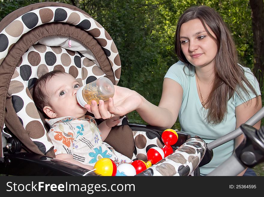 Mother feeding newborn son with feeding bottle