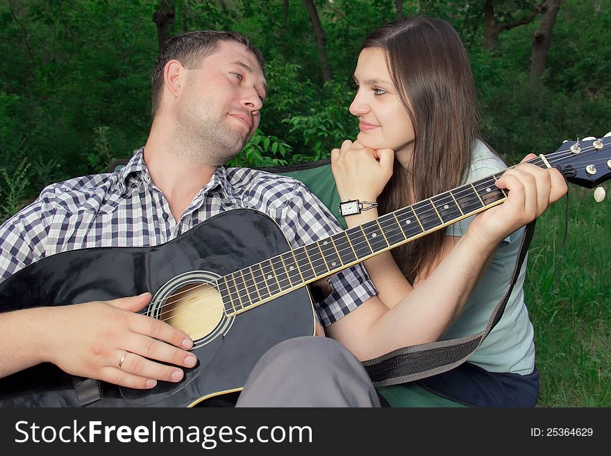 Romantic young couple embracing playing guitar outdoor