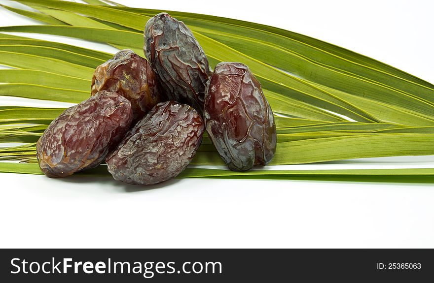 Ripe dates and palm leaves on white background