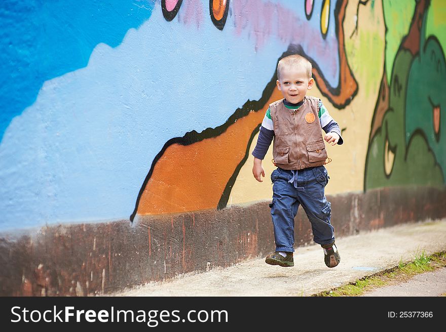 Cheerful boy running on a colored background. Cheerful boy running on a colored background