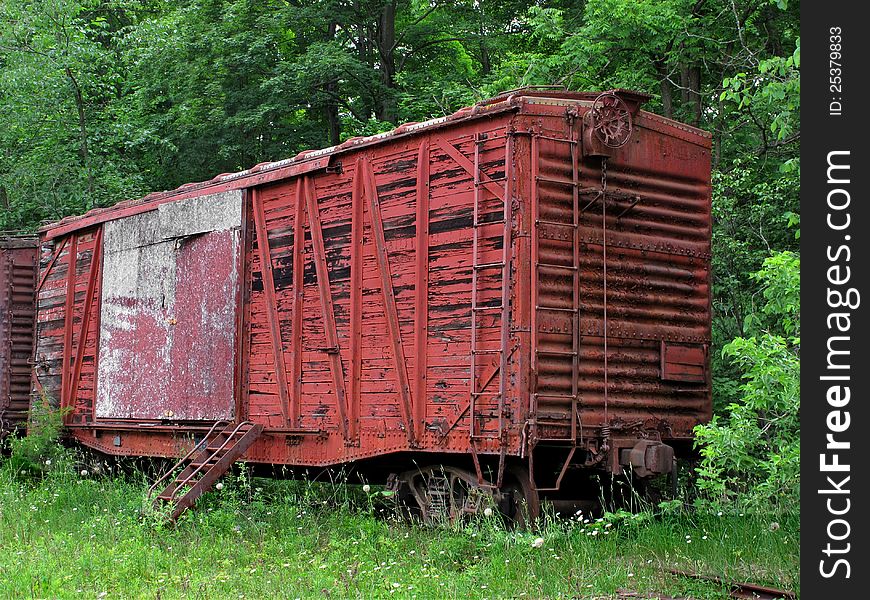 Old, weathered, and abandoned red wooden train boxcar sitting the woods. Old, weathered, and abandoned red wooden train boxcar sitting the woods.