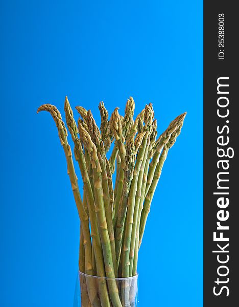 Bunch asparagus stalks photographed against a blue background
