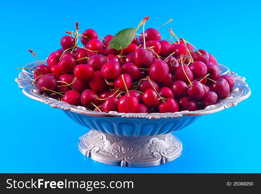 Cherry poured into a silver vase photographed against a blue background. Cherry poured into a silver vase photographed against a blue background