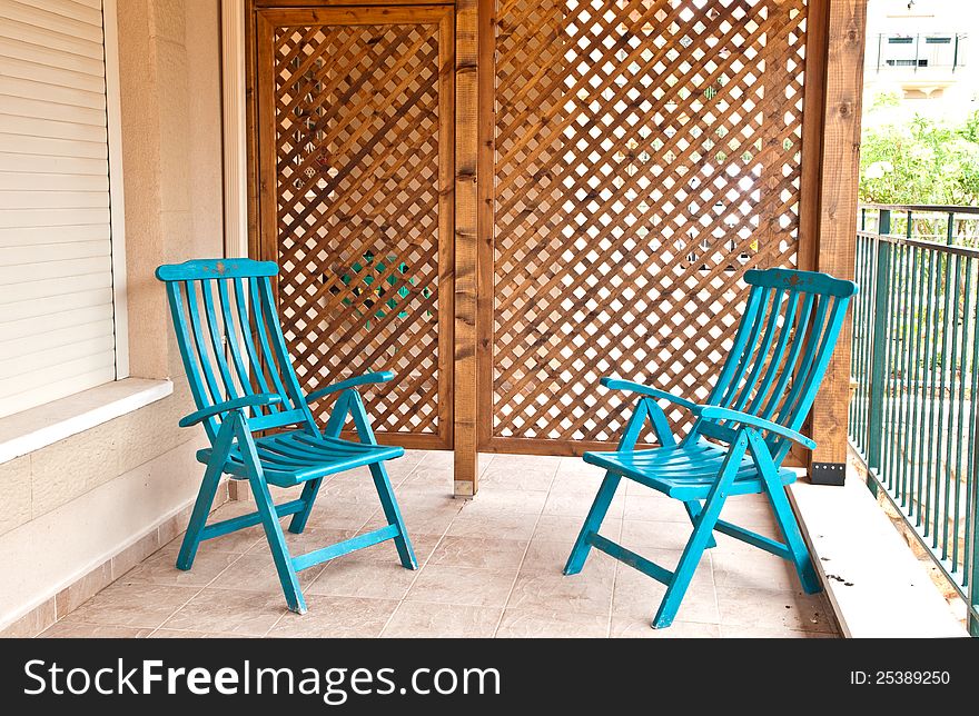 Fragment of a village house with a wooden lattice wall and two wooden chairs. Fragment of a village house with a wooden lattice wall and two wooden chairs