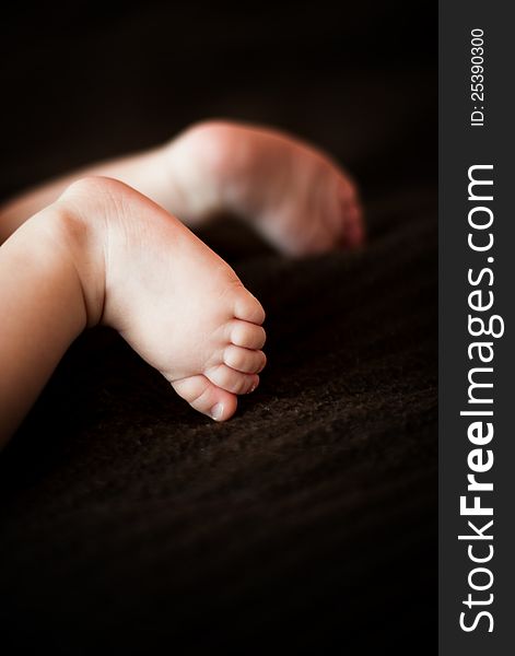 Small baby feet on a dark brown blanket