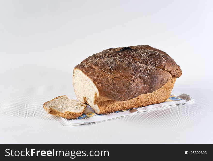 Loaf and slice of white wheat bread on the table-napkin. Loaf and slice of white wheat bread on the table-napkin