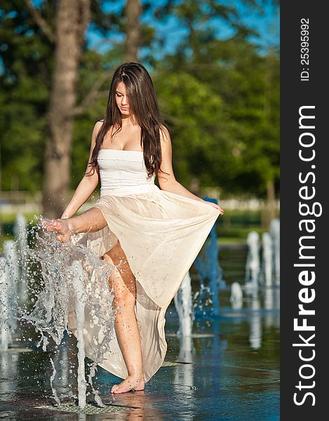 Beautiful Brunette Girl Playing At  Water Fountain