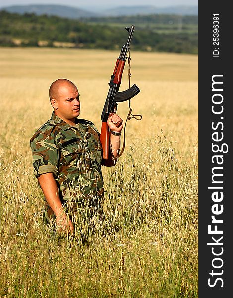 Soldier in a wheat field holding AK-47 assault-rifle. Soldier in a wheat field holding AK-47 assault-rifle