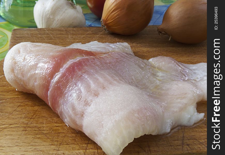 Raw fillet of a fish Pangasius hypophthalmus on a wood board. Raw fillet of a fish Pangasius hypophthalmus on a wood board