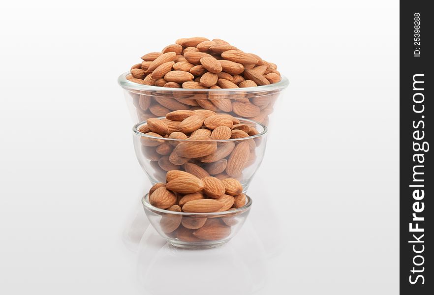 Pile of almond and glass bowls over white background. Pile of almond and glass bowls over white background