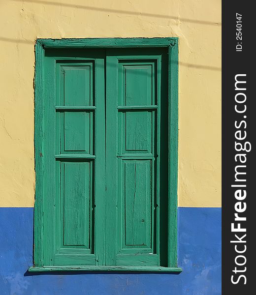 Green window with wooden blend case in colored facade on La Gomera Island