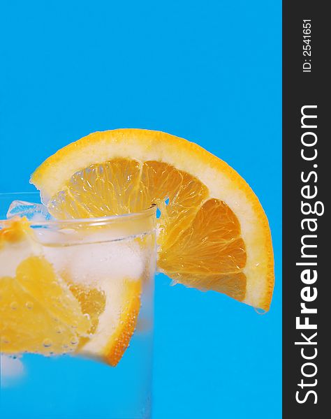 Bright juicy oranges in a glass on a blue background. Bright juicy oranges in a glass on a blue background