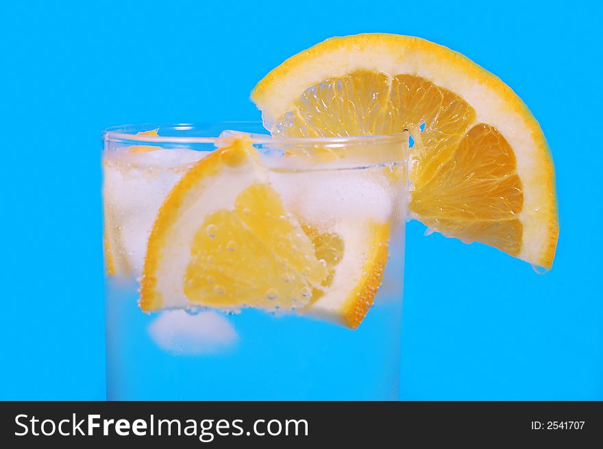 Bright juicy oranges in a glass on a blue background. Bright juicy oranges in a glass on a blue background