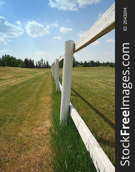 White fences around green farm area. White fences around green farm area