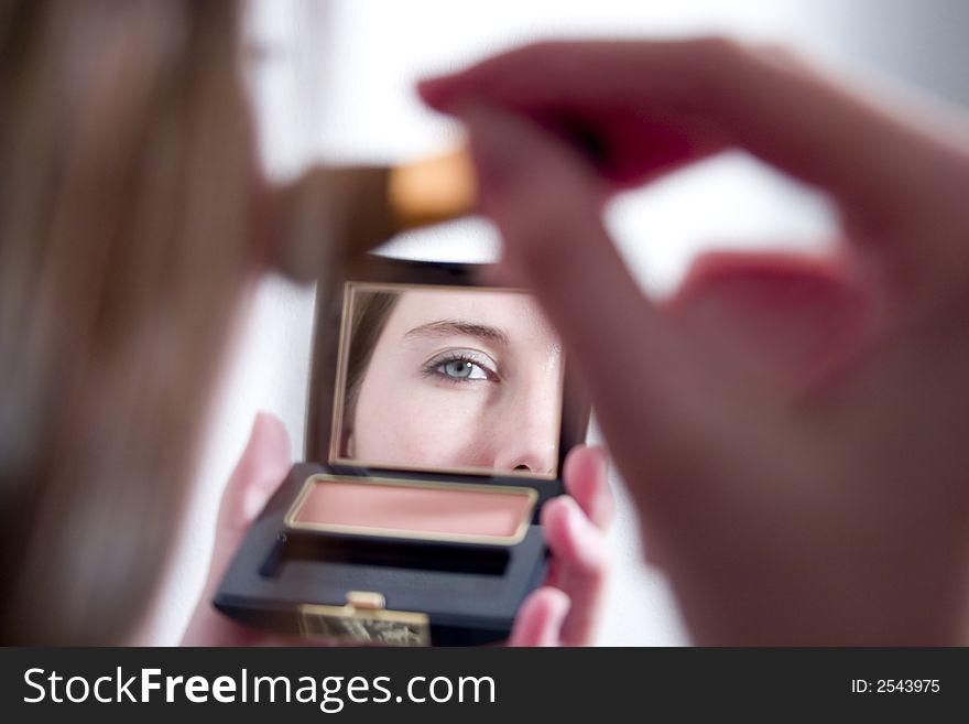 Mid adult woman applying make-up in the mirror; eye reflection. Mid adult woman applying make-up in the mirror; eye reflection
