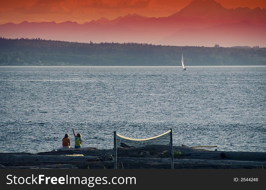 Two girls at the beach in Edmonds, WA with a sailboat and volley ball net. Two girls at the beach in Edmonds, WA with a sailboat and volley ball net