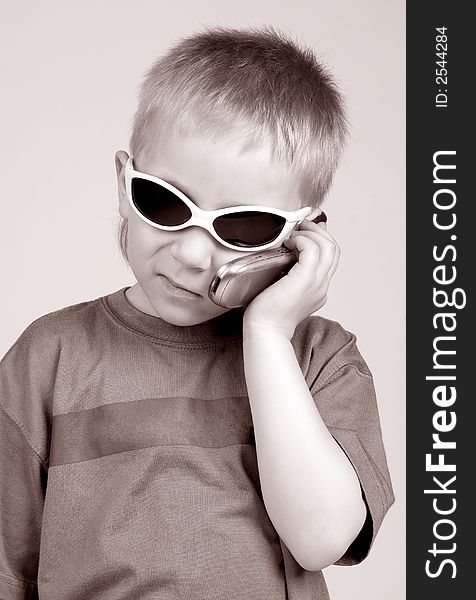The boy talks by mobile phone on a grey background. The boy talks by mobile phone on a grey background
