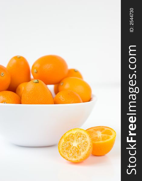 A bunch of Kumquats halved and in a white bowl