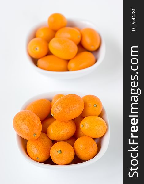 A bunch of Kumquats in two white bowls