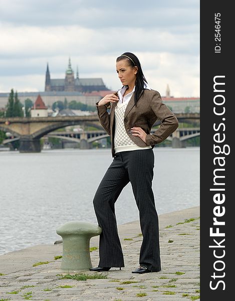 Standing young slim woman at the river bank, Prague castle in background. Standing young slim woman at the river bank, Prague castle in background