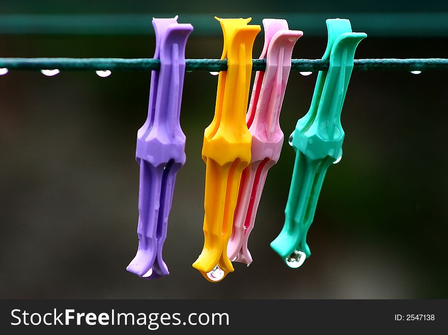 Plastic pegs on a clothes line with rain drops. Plastic pegs on a clothes line with rain drops