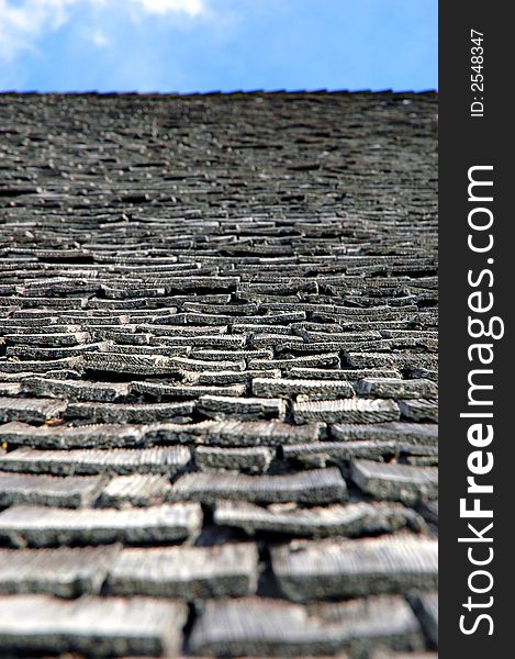 Close up of old, worn shingles leading up to the sky.