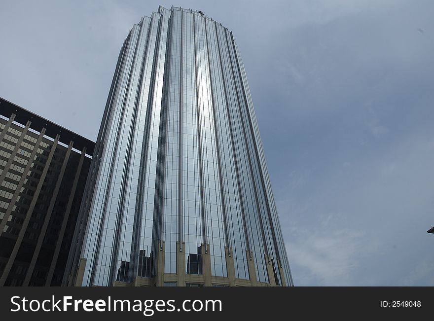 Glass tower with sun shinning on it.  Clouds surrounding tower.  Shot is facing up. Glass tower with sun shinning on it.  Clouds surrounding tower.  Shot is facing up.