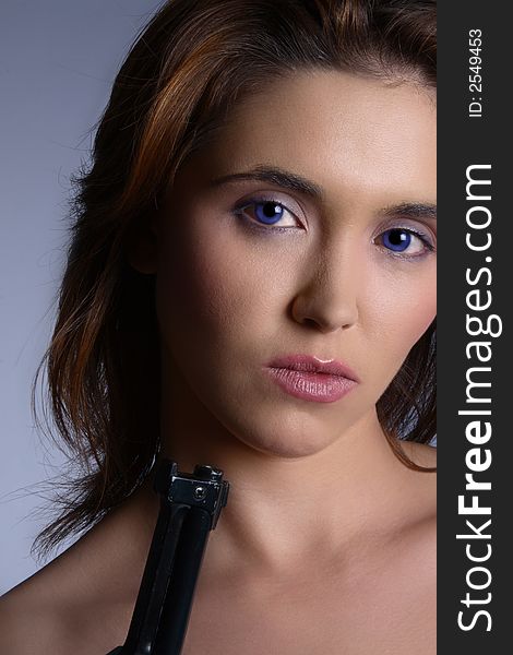 Beautiful brunette woman with very blue eyes holding a gun and looking at the camera. Beautiful brunette woman with very blue eyes holding a gun and looking at the camera