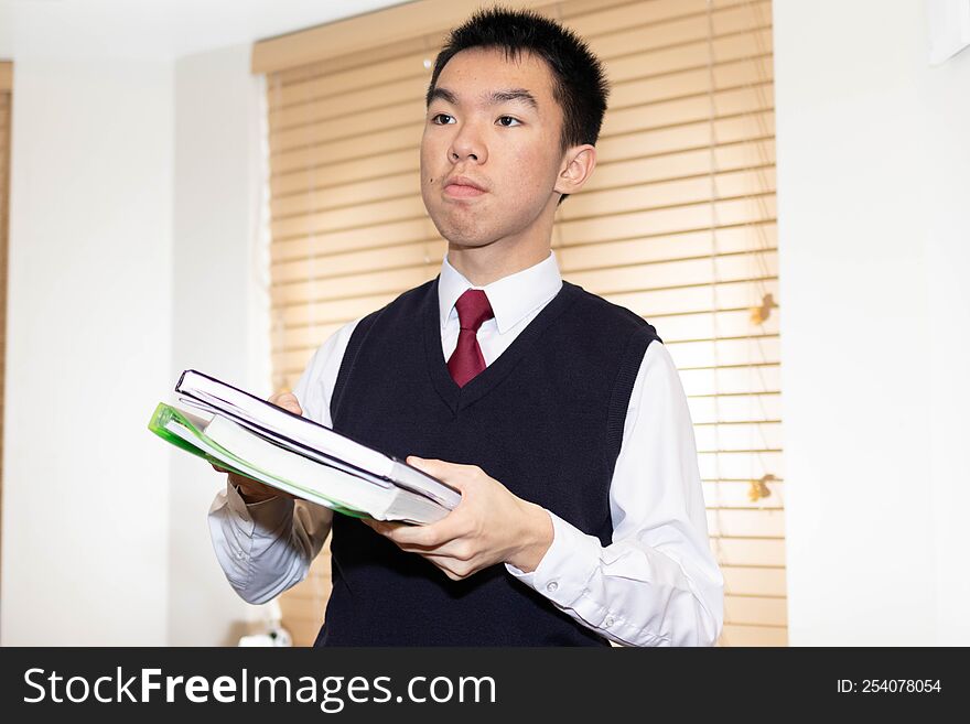 Student wearing uniform holding up textbooks