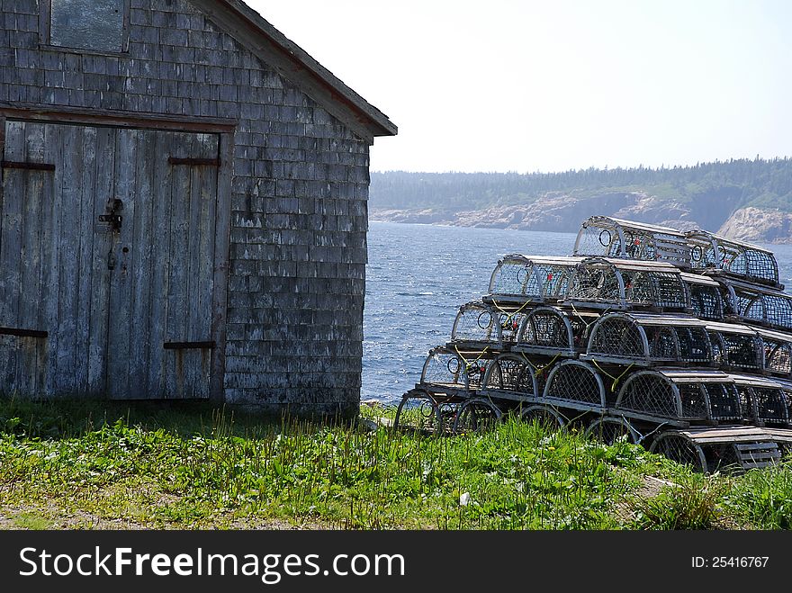 A tall stack of lobster pots stand beside a down east shack by the bay. A tall stack of lobster pots stand beside a down east shack by the bay