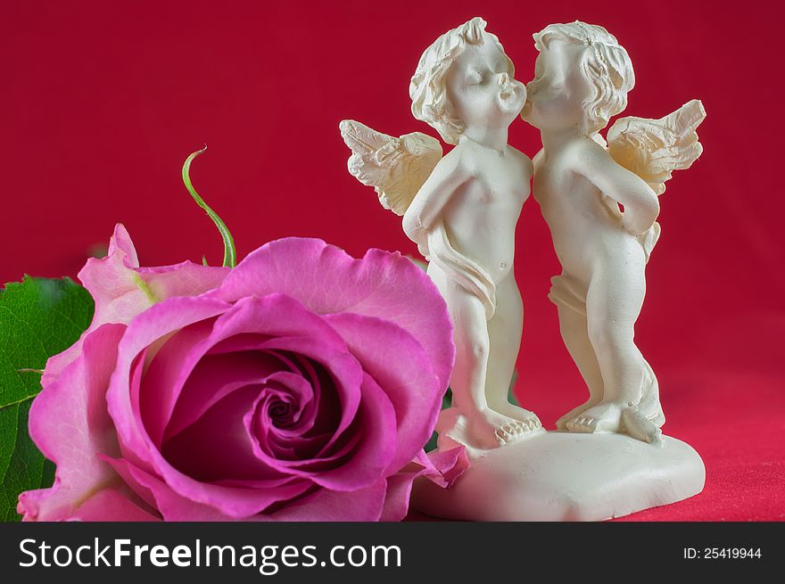 Angels kissing with pink rose on red background. Angels kissing with pink rose on red background