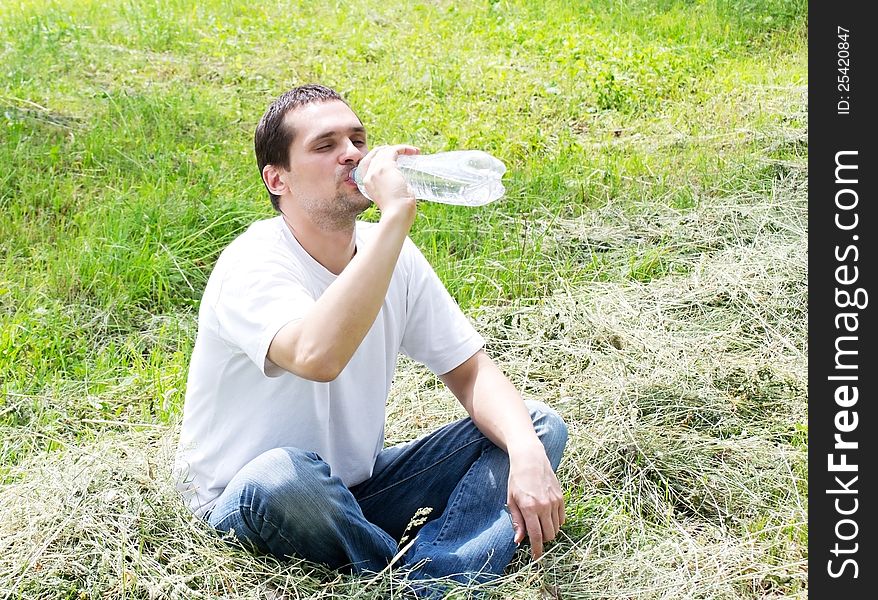 Young man eagerly drinking water from plastic bottles