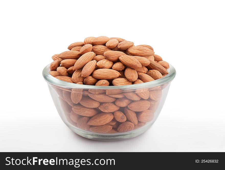 Pile of  almonds in transparent glass small bowl  over white background